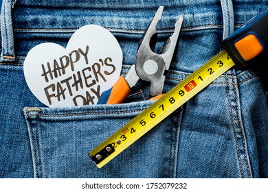 ジーンズのポケットにペンチを入れた背景と、「父の日おめでとう」と書かれたハート。お父さんにプレゼント。幸せな父の日のコンセプトです。