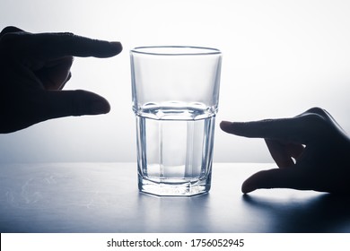 Handen meten op glas met een leeg deel en links water, glas halfvol houdingsconcept, crisis- en kansenperspectief