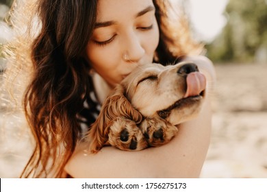 Jonge vrouw knuffelen en zoenen haar hondje, cocker spaniel ras pup.