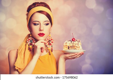 ケーキと赤毛の女の子をスタイルします。背景のボケ味のある写真。