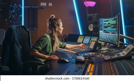 Nữ kỹ sư âm thanh xinh đẹp làm việc trong phòng thu âm nhạc, sử dụng bảng trộn và phần mềm để tạo âm thanh hiện đại. Nhạc sĩ Creative Girl Artist Làm việc trên Bàn điều khiển để Sản xuất Bài hát Mới