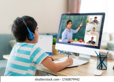 E-Learning der asiatischen Jungenschüler-Videokonferenz mit Lehrer und Klassenkameraden am Computer im Wohnzimmer zu Hause. Homeschooling und Fernunterricht, Online, Bildung und Internet.
