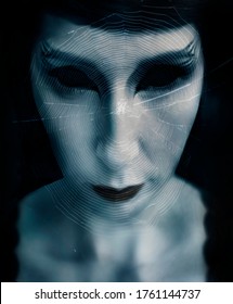 女性の顔は黒い背景にクモの巣で覆われています。ハロウィーンの不気味な生き物の肖像画。邪悪な女性の黒い目のクローズ アップ。幻想的なフェイスアートを施したゾンビウーマン。カメラ目線の女の子。