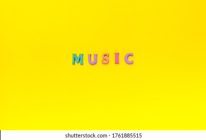 MUSIC multi-colored wooden letters lettering word over a Yellow background. Music lover concept