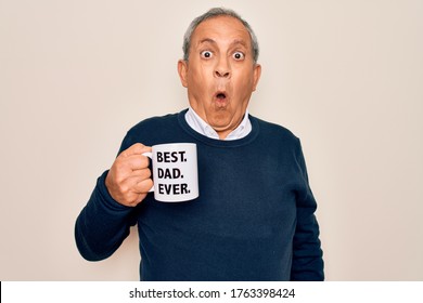 Senior man drinking cup of coffee with best dad ever message over white background scared in shock with a surprise face, afraid and excited with fear expression