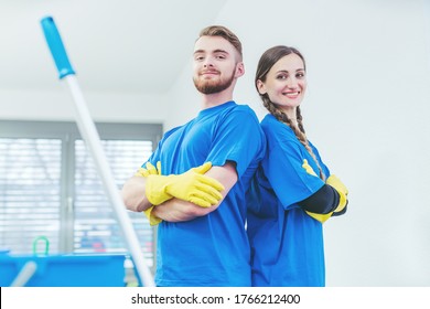 Limpiadores orgullosos de su servicio con los brazos cruzados, equipo de mujer y hombre