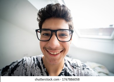 Remaja laki-laki berkacamata mengambil selfie