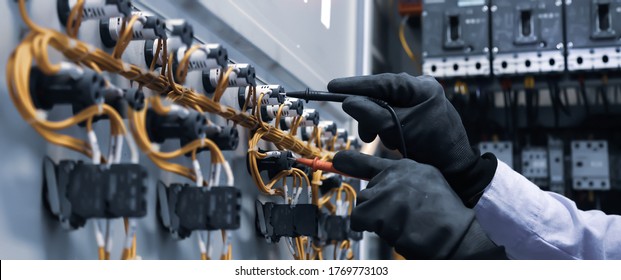 Elektrotechnisch ingenieur die digitale multimeter-meetapparatuur gebruikt om de elektrische stroomspanning te controleren op de stroomonderbreker in het hoofdstroomverdeelbord.