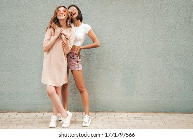 Two young beautiful smiling hipster girls in trendy summer clothes.Sexy carefree women posing on street background in sunglasses. Positive models having fun and hugging