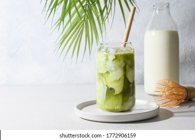 Es teh matcha hijau dicampur dengan es batu dan susu dalam gelas latte di atas putih. Ruang untuk teks. Merapatkan.