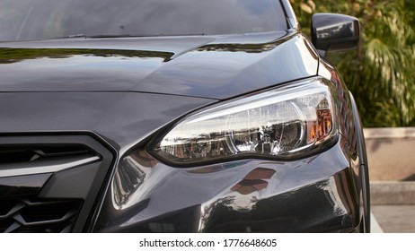 Nariz de vehículo de ratón gris con luces apagadas con destellos y reflejos de la naturaleza con pavimento de fondo