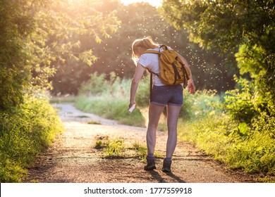 Woman applying insect repellent against mosquito and tick on her leg during hike in nature. Skin protection against insect bite