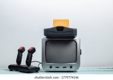 Máy thu truyền hình cũ với bảng điều khiển trò chơi cổ điển, cần điều khiển trên nền tường trắng. Chơi game cổ điển. Thập niên 80
