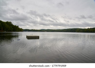 A square wooden platform on the water surrounded by trees under the cloudy sky in Canada