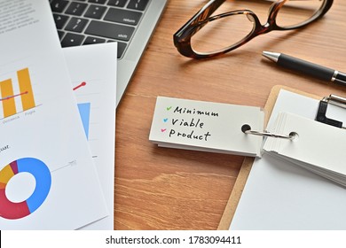 Hay una hoja de papel con un gráfico impreso, un sujetapapeles y un libro de vocabulario abierto sobre el escritorio. Ahí está la palabra Producto Mínimo Viable.