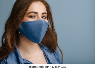 Hermosa mujer con elegante máscara protectora azul. Accesorio de moda de moda durante la cuarentena de la pandemia del coronavirus. Cierra el retrato de estudio. Copiar, espacio vacío para texto