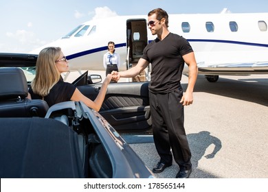 Bodyguard hilft eleganter Frau, die am Flughafenterminal aus dem Auto steigt