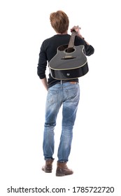 Achteraanzicht van jonge rocker-gitarist die wegloopt met akoestische gitaar op schouder. Volledige lichaamslengte geïsoleerd op een witte achtergrond.
