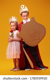 Un ragazzo e una ragazza carini in costumi da principe e principessa posano su uno sfondo giallo. Sogni d'infanzia. Fantasia, immaginazione. Ritratto in studio.