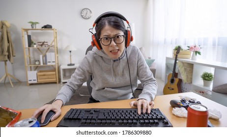 面白い若い女性ゲーマー ヘッドセット コンピューターでビデオ ゲームをプレイし、驚きでカメラを見ています。自宅で夏休みに余暇にコンピューターを使用して驚いたアジアの女性の肖像画。