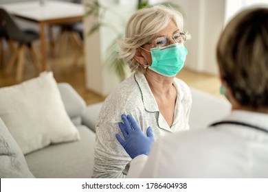 ウイルスの流行中に自宅を訪問している医師と話している間、保護用のフェイスマスクを着用した年配の女性。