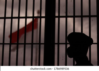 マスクを着けた男が刑務所の中でインドネシアの国旗を見つめている