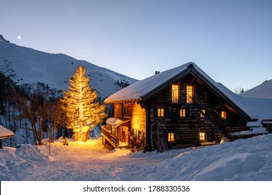 Senja di Holiday Hut di Pegunungan Alpen Swiss dengan Salju dan Cahaya Pohon