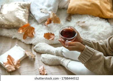自宅での居心地の良い秋、お茶を飲み、本を休んでいる女性。居心地の良い生活様式。コンポジションのボディパーツ。