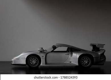 silver supercar toy on black table. Wall in the background.