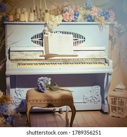 Old blue piano in the rays of light. Retro musical instrument with flowers, notes and candles
