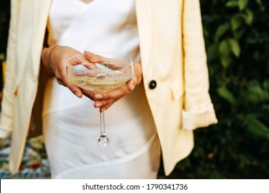 Vrouw gekleed in witte cocktailjurk met een coupe champagne.