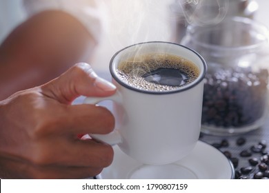 Mann füllt Tasse mit heißem, frischem Kaffee an einem Morgen zu Hause. Nahaufnahme