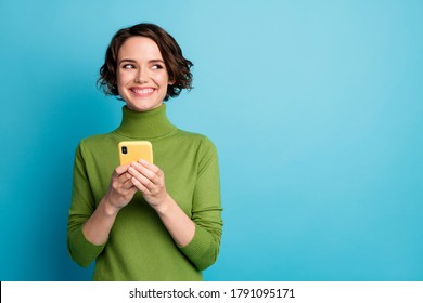 Retrato de uma garota alegre e positiva usando um smartphone, com espaço para texto, compartilhando notícias nas redes sociais, vestindo um suéter estiloso e moderno, isolada em um fundo azul.