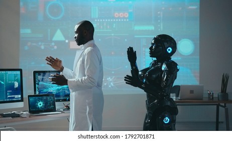 Black automated robot repeating moves after male scientist in futuristic high tech laboratory. Innovations. Robotic industry. Artificial intelligence. Cooperation.
