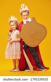 Un bel bambino e una bambina giocano insieme a Principe e Principessa. Sogni d'infanzia. Fantasia, immaginazione. Ritratto in studio su sfondo giallo.