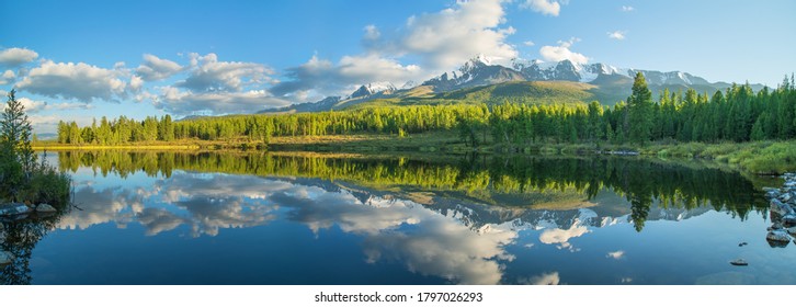 Malerischer Bergsee am Sommermorgen, Altai. Schöne Reflexion von Bergen, Himmel und weißen Wolken.