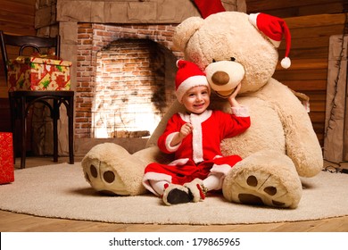 Christmas picture of Kid in Santa costume with big teddy bear