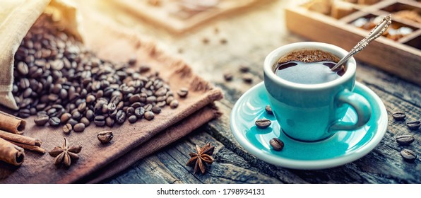Eine türkisfarbene Tasse aromatischen schwarzen Kaffees und Kaffeebohnen auf dem Tisch. Morgenkaffee Espresso zum Frühstück in einer schönen türkisfarbenen Tasse.