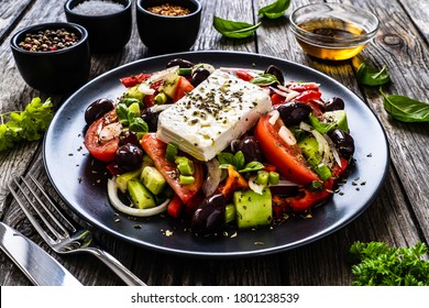 Verse Griekse salade - fetakaas, tomaten, komkommer, rode peper, zwarte olijven en ui op houten tafel