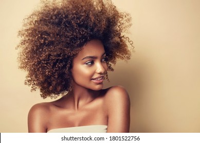Retrato de belleza de mujer negra afroamericana con piel limpia y saludable sobre fondo beige. Cuidado de la piel y cosmética. Sonriente hermosa chica afro. Cabello rizado