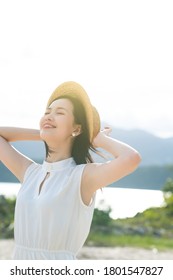 Niña china asiática con vestido blanco de una pieza con sombrero. Cielo azul verano brisa aireada al aire libre