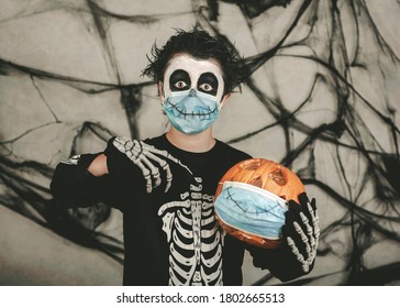 Happy Halloween,kid wearing medical mask in a skeleton costume with halloween pumpkin over gray background