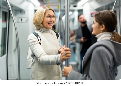 Potret wanita dewasa berbicara ramah dengan sesama pengelana di mobil kereta bawah tanah modern..