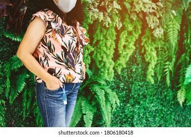 Mini portable alcohol gel bottle to kill Corona Virus(Covid-19) hanging on belt loop of woman' s jeans with plants background. New normal lifestyle. Health care concept. Selective focus on alcohol gel