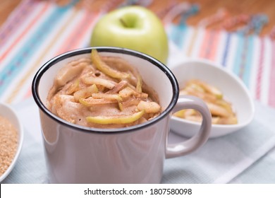 Torta di mele in tazza con ingredienti e fette di mela sopra su legno