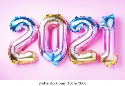 Colorful foil balloons made numbers 2021 on pink background with light bokehs. Banner, copy space. Happy new year celebration party. Greetings and congratulation concept.