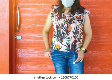 Mini portable alcohol gel bottle to kill Corona Virus(Covid-19) hanging on belt loop of woman' s jeans with plank background. New normal lifestyle. Health care concept. Selective focus on alcohol gel