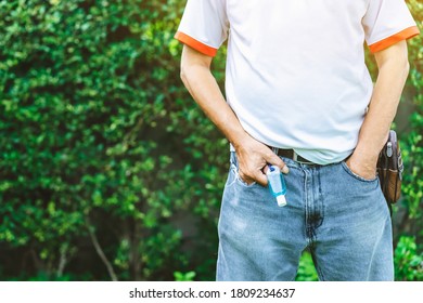 植物の背景を持つ男性のジーンズのベルトループにぶら下がっているコロナウイルス(Covid-19)を殺すミニポータブルアルコールジェルボトル. ニューノーマルなライフスタイル。ヘルスケアのコンセプト。アルコールジェルの選択と集中