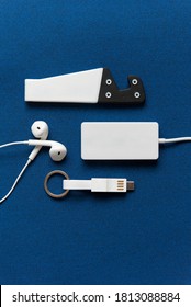 Zubehör aus einem Smartphone-Kit mit Handyständer, Kopfhörern, USB-Schlüsselring vor dunkelblauem Hintergrund. Platz für Logo