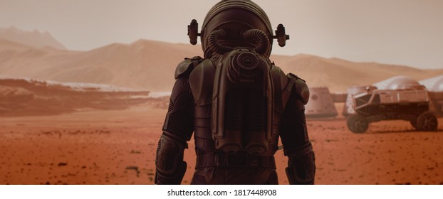 Back view of astronaut wearing space suit walking on a surface of a red planet. Martian base and rover in the background. Mars colonization concept